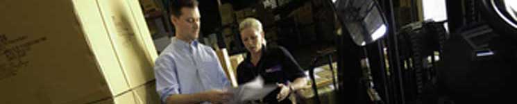 Des employés de FedEx Trade Networks examinant de la documentation de fret dans un entrepôt.